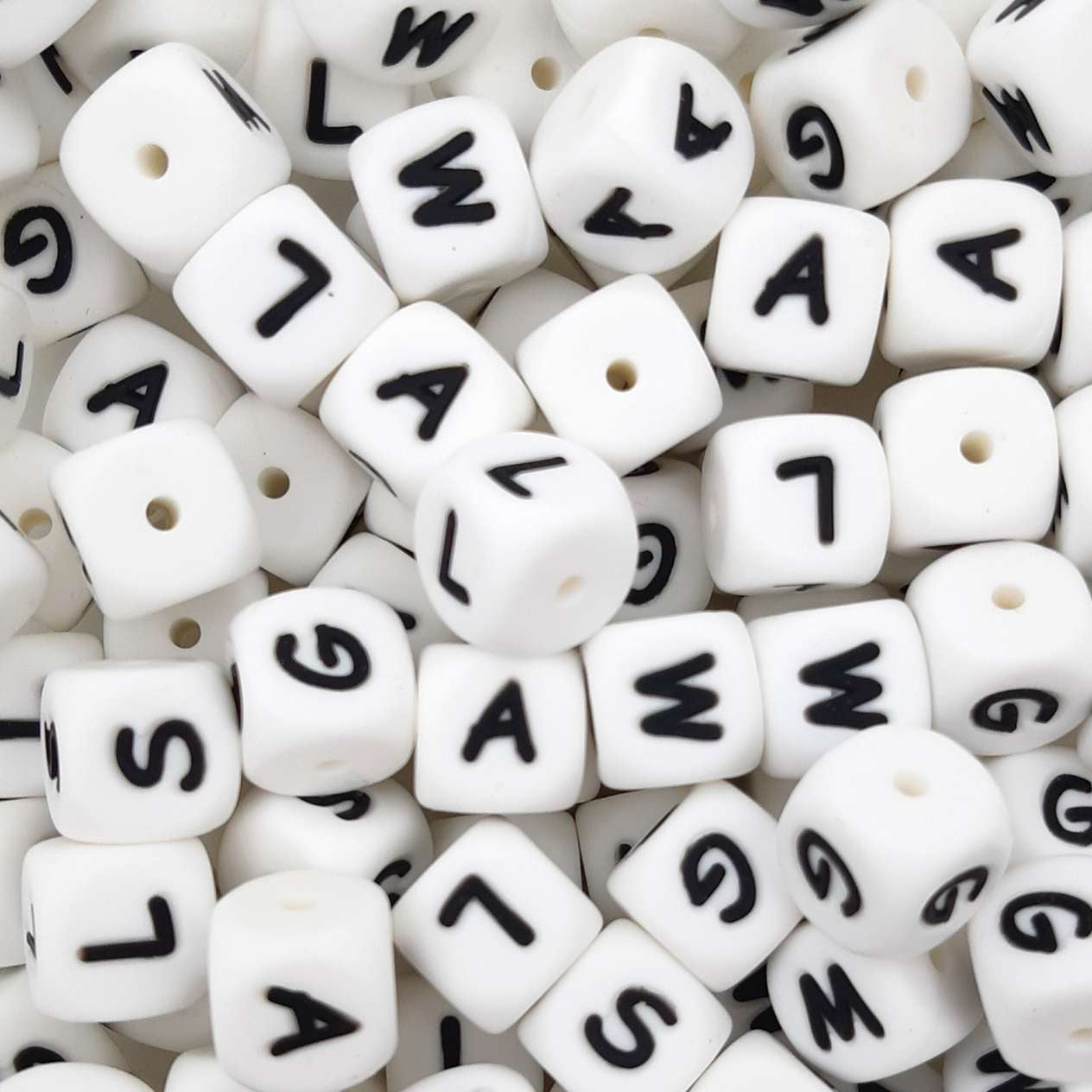 White beads with black letters scattered on a white background