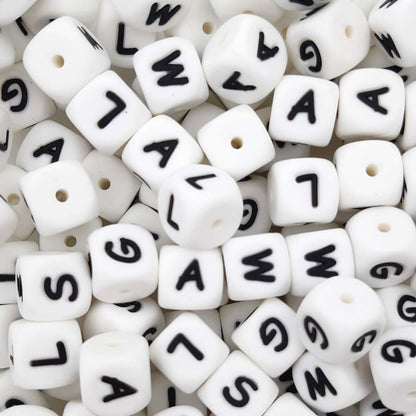 White beads with black letters scattered on a white background