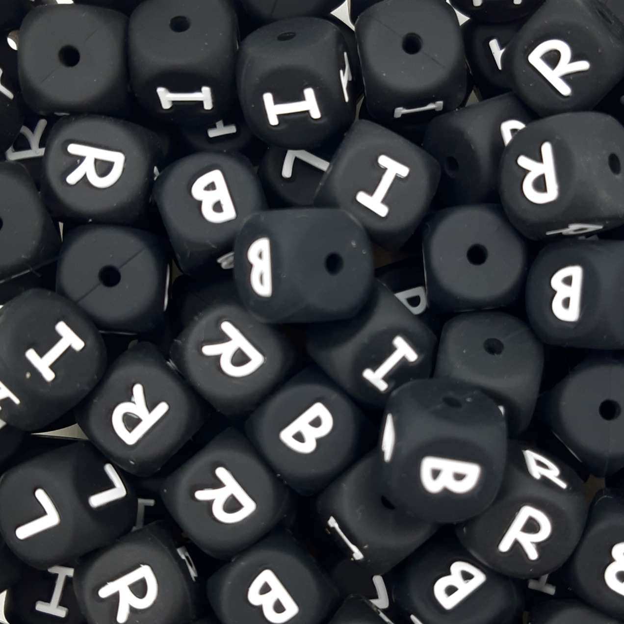 Black letter beads with white letters scattered on a black background