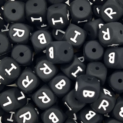 Black letter beads with white letters scattered on a black background