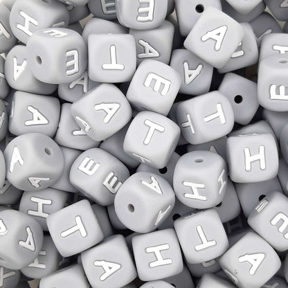 Gray letter beads with white letters scattered on a flat surface
